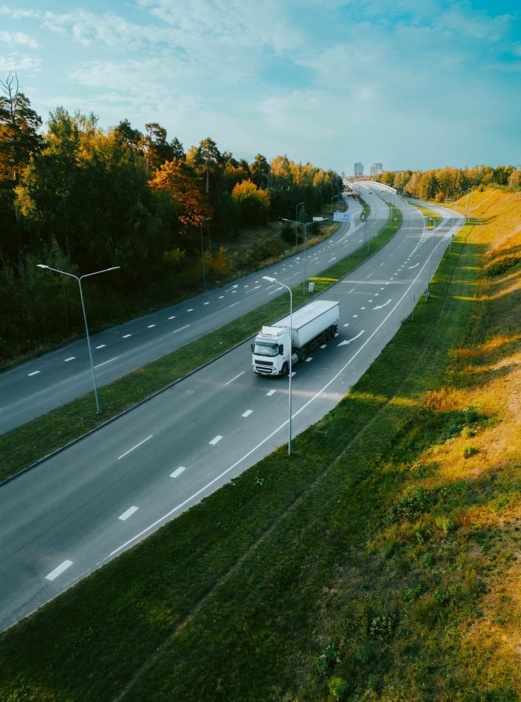Top view of a truck driving along a highway road in evening time under a sunny blue sky Top view of a truck driving along a highway road in evening time under a sunny blue sky